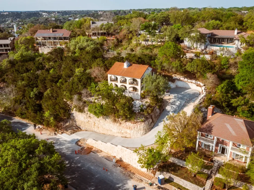 Home 6 Ledge Mountain residential development, Austin TX — aerial view of hillside site with retaining walls and driveway construction