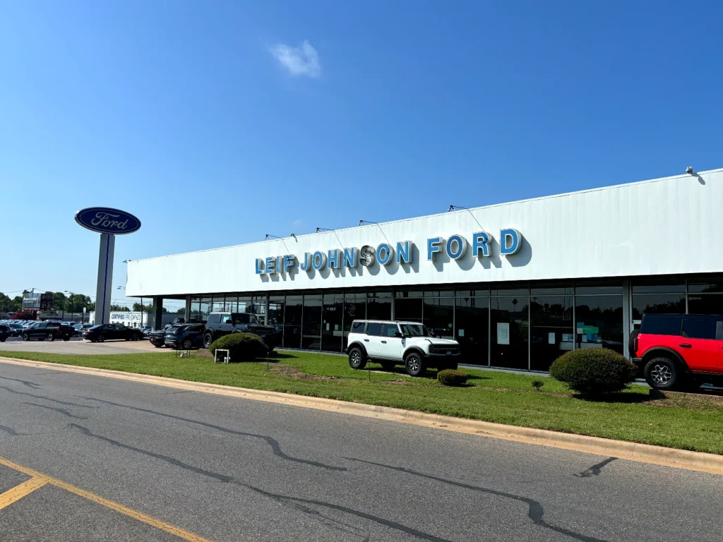 Home 5 Leif Johnson Ford showroom seen from the parking lot, with the long glass storefront, landscaped curb and vehicles on display.