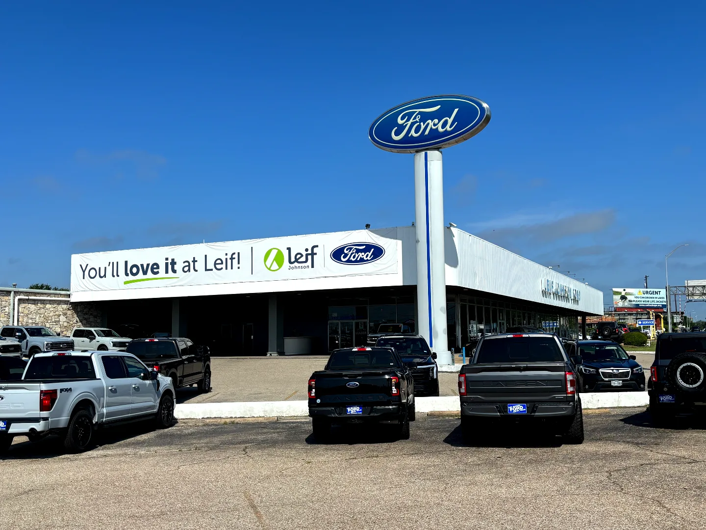 Leif Johnson Ford dealership in Austin, Texas, with the Ford pylon sign and new trucks in the front parking lot
